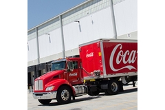 Image Coca-Cola delivery truck parked at warehouse loading dock, beverage distribution and logistics concept
